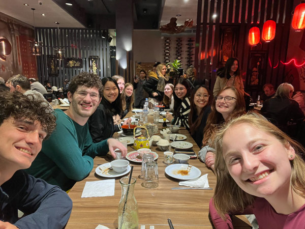 A group of study abroad students seated at a restaurant and smiling at the camera