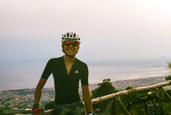 A person wearing a helmet and standing on a fence with city and ocean views