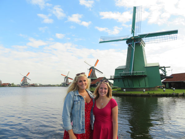 朋友们站在荷兰的水和风车前