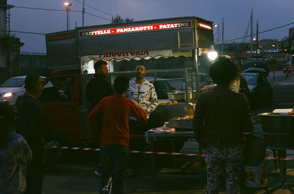 A group of people standing around a food truck at night