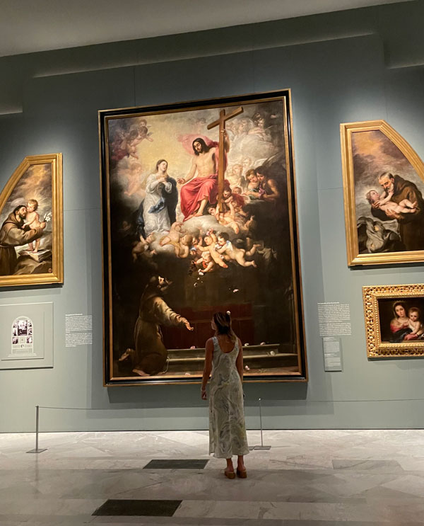 A study abroad student looking up at a large painting in a museum