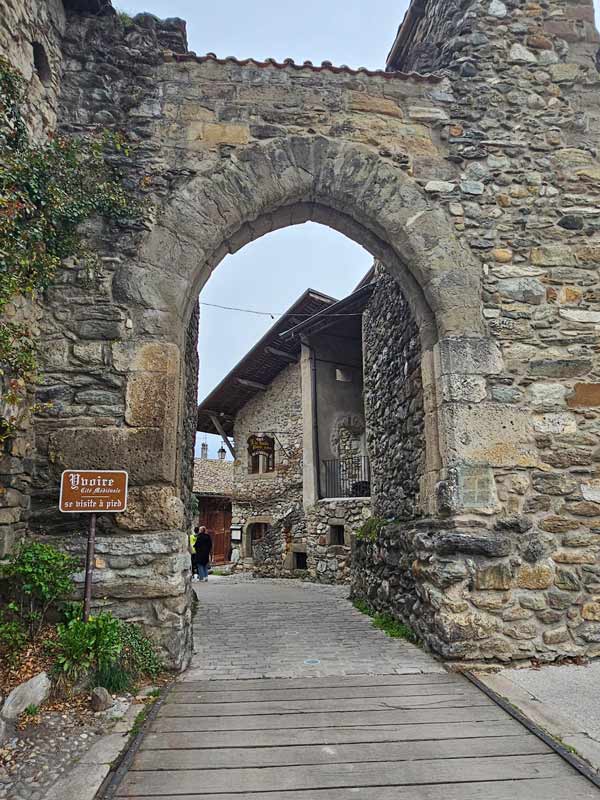 A stone archway standing over a brick path leading into a village