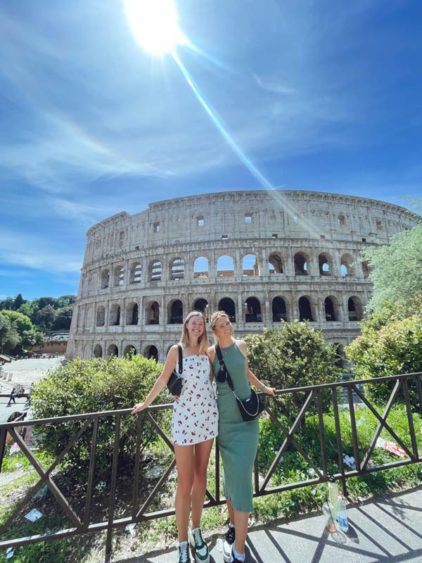 两个留学生在一座大型圆形建筑前摆姿势拍照