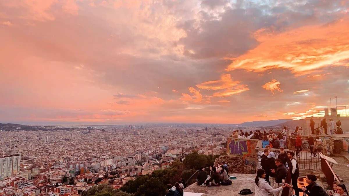 在西班牙巴塞罗那，人们在卡梅尔堡顶上观看日落