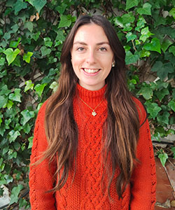 A person in a red sweater smiling at the camera.