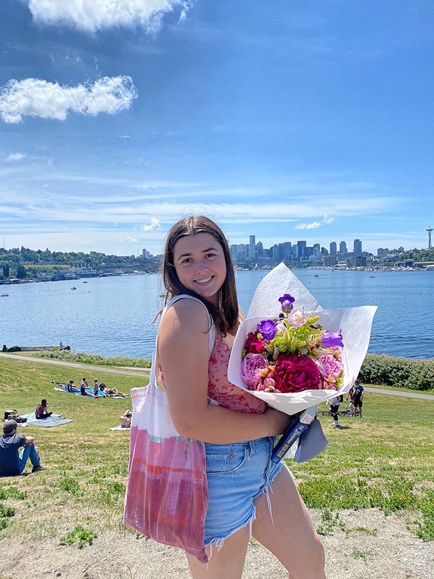 a study abroad student holding flowers smiling