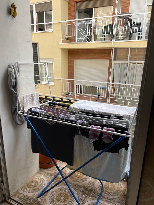 clothes hanging on a drying rack on a balcony