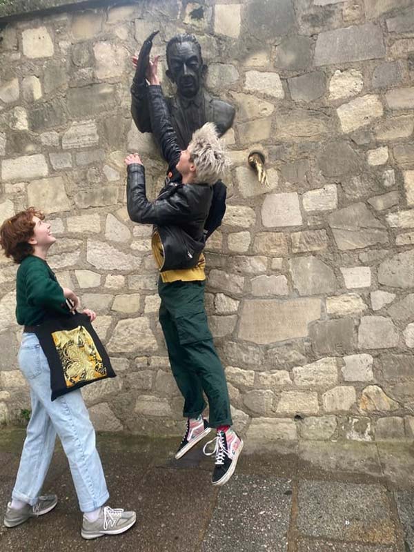 A study abroad student jumping up to a statue of a person