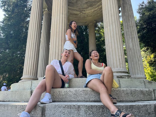 A group of study abroad students sitting on steps with columns.