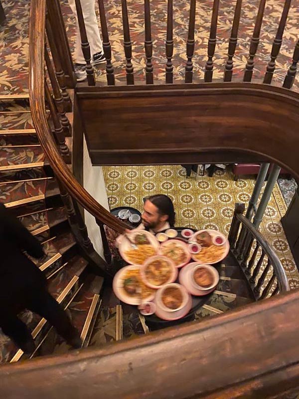 A waiter carrying a tray of food on a staircase