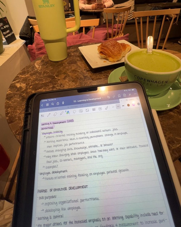 An ipad with study abroad notes sitting on a table with a coffee cup and croissant on a plate