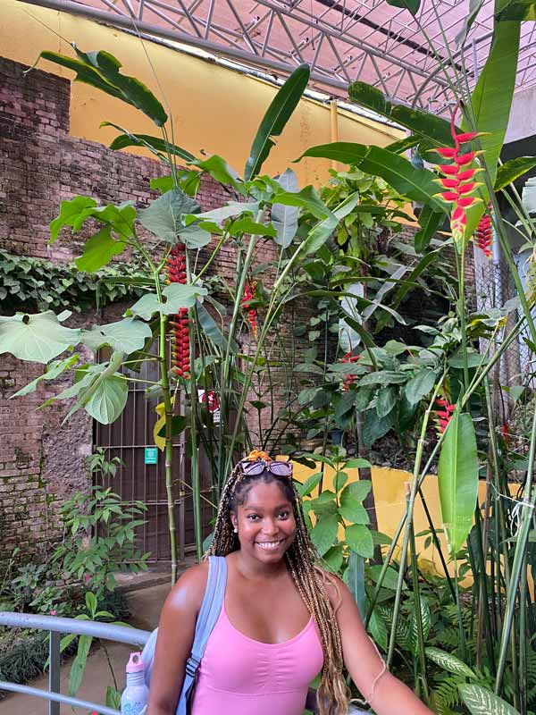 A study abroad student in front of plants
