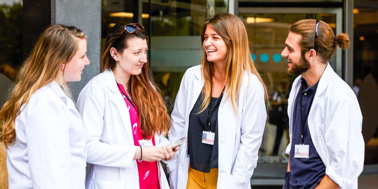 Students in lab coats gathered together