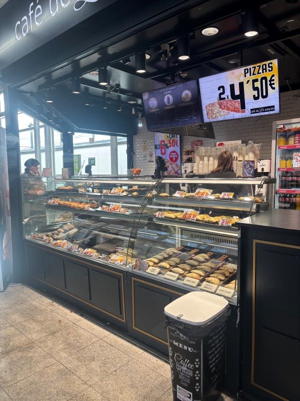 A small coffe shop's storefront, featuring a display case full of pastries