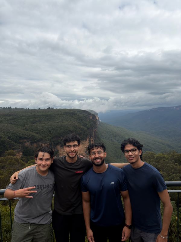 A group of study abroad students smiling while standing in a group, with a mountainous landscape behind them