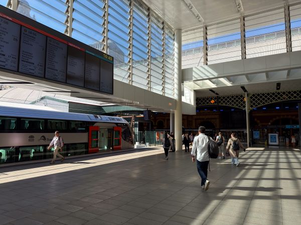 A well-lit train platform with a train in the distance underneath a digital timetable board