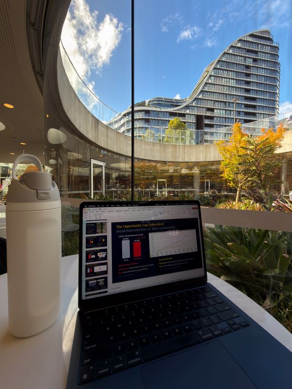 A laptop sitting on a desk next to a white water bottle in a bright interior space