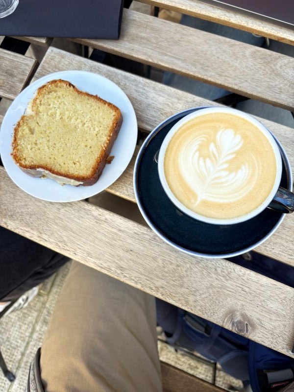 A slice of cake and a cup of coffee on small ceramic plates on a wooden table