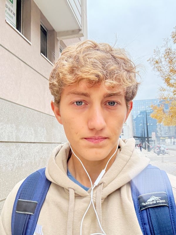 A study abroad student taking a selfie while wearing a backpack and headphones outdoors