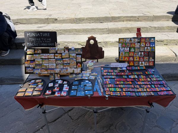 A table outdoors featuring many small colorful magnets