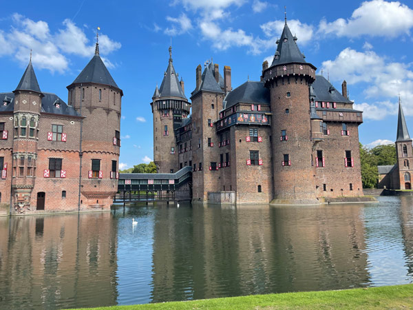 A castle with a body of water with Kasteel de Haar in the background