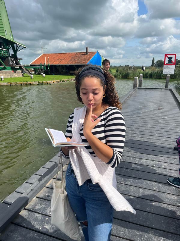 A study abroad student standing on a dock holding a book