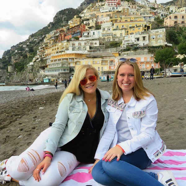Friends sitting on blanket at beach along Amalfi Coast in Italy