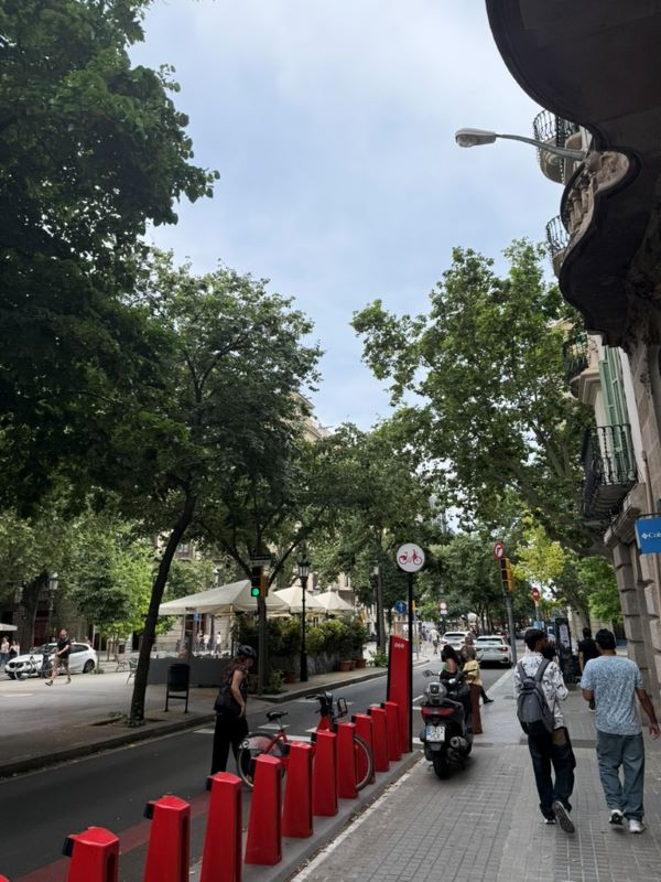 People walking along a city street with a bike docking station lining one side of the street