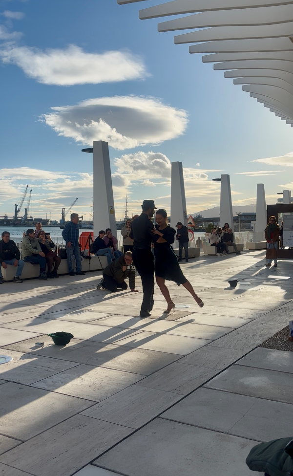 Two people dancing closely together outdoors, surrounded by a seated crowd
