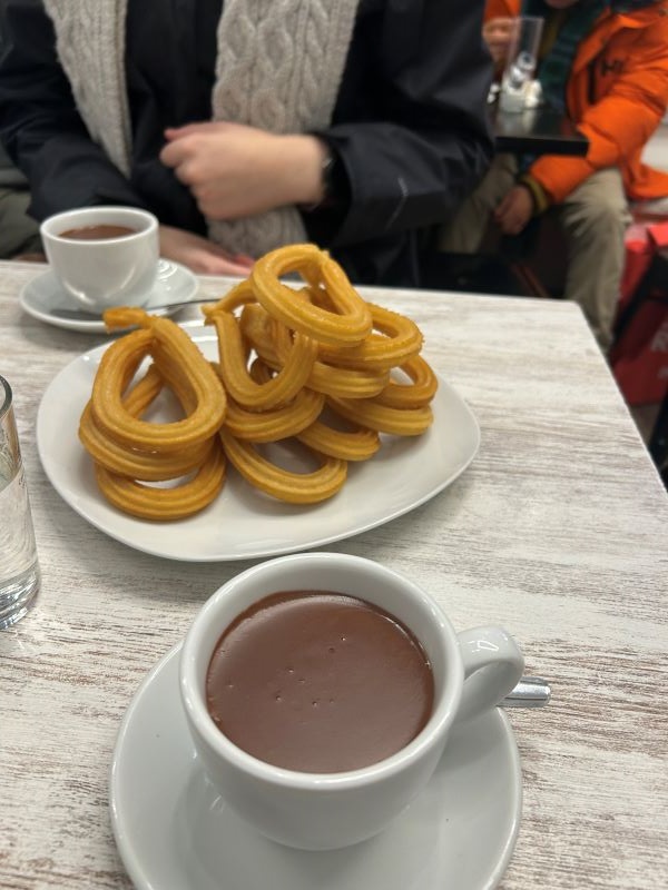 A plate of churros and a cup of chocolate sauce sitting on a table
