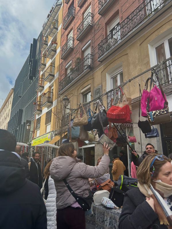 A group of people buying and selling handbags on a busy street