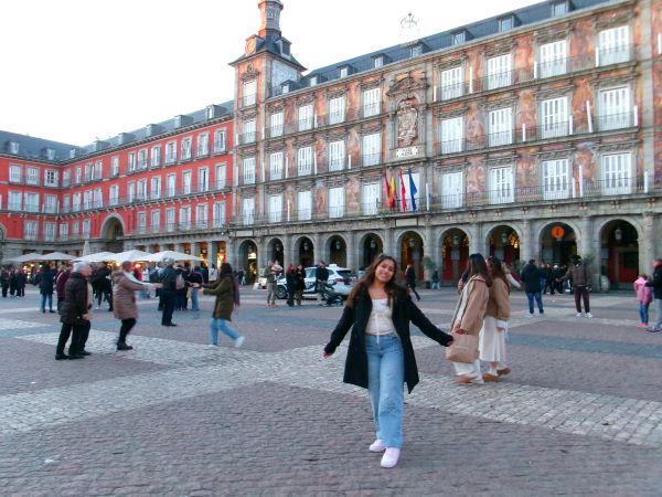 A study abroad student standing in a large plaza and smiling at the camera