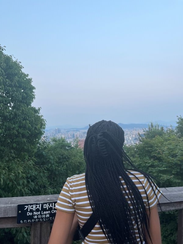 A study abroad student seen from behind looking out over a vast city landscape from above