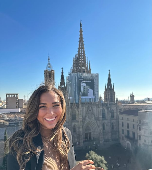 A person smiling in front of a cathedral