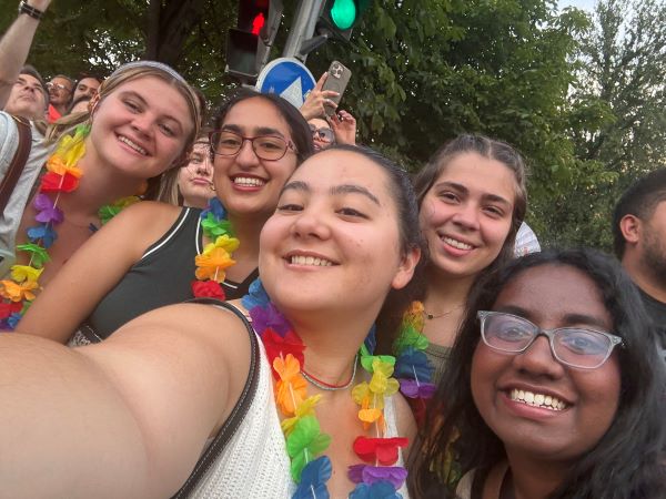 Five stusy abroad students taking a selfie while wearing brightly-colored artificial flower leis and smiling at the camera