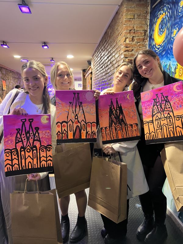 Four study abroad students holding their paintings from class