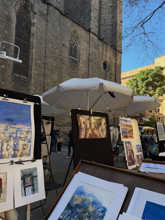 Paintings set up at outdoor artists' easels under white umbrellas