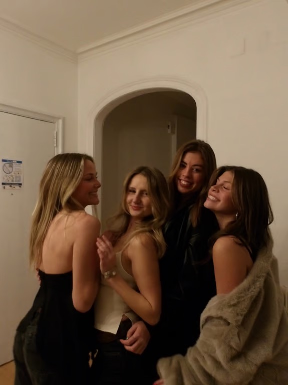 Four study abroad students gathered together, all smiling, with two looking at the camera and two looking away from it