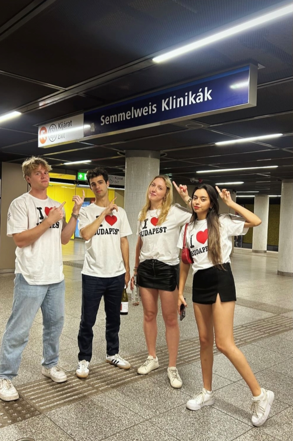 Four study abroad students posing for photo in matching shirts at train station