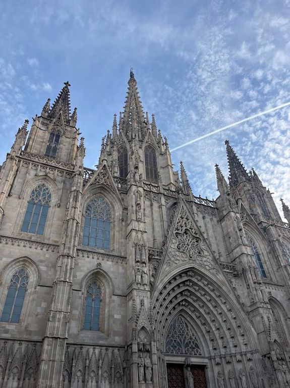 An intricately decorated cathedral exterior as seen from below and in front of a bright blue sky