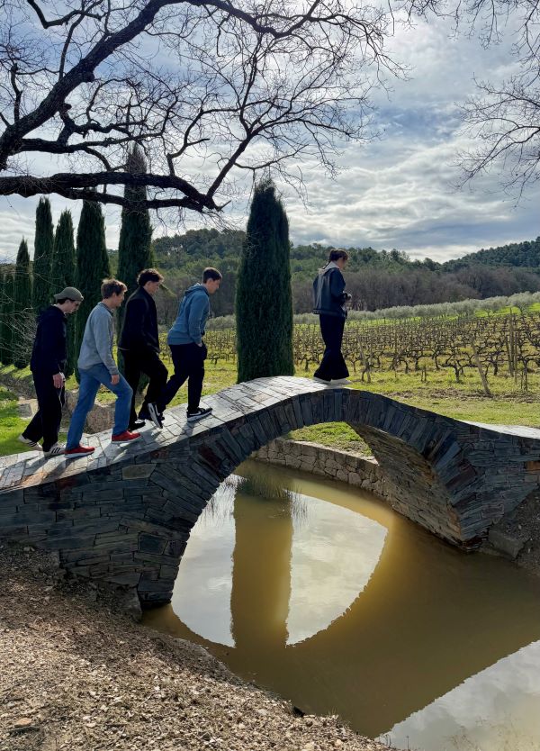 Five study abroad students walking across a small bridge over a small body of water