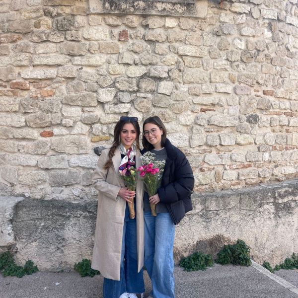 Two study abroad students posing for photo both holding bouquets of flowers