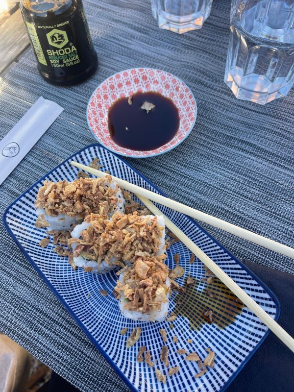 Plated sushi roll with chop stickers and soy sauce