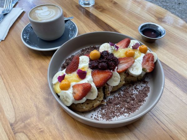 Plated pancakes with fruit on top and cup of coffee