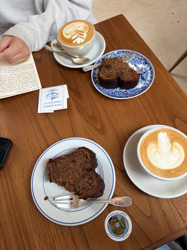 Slices of bread and cups of coffee on small plates on a small wooden indoor table