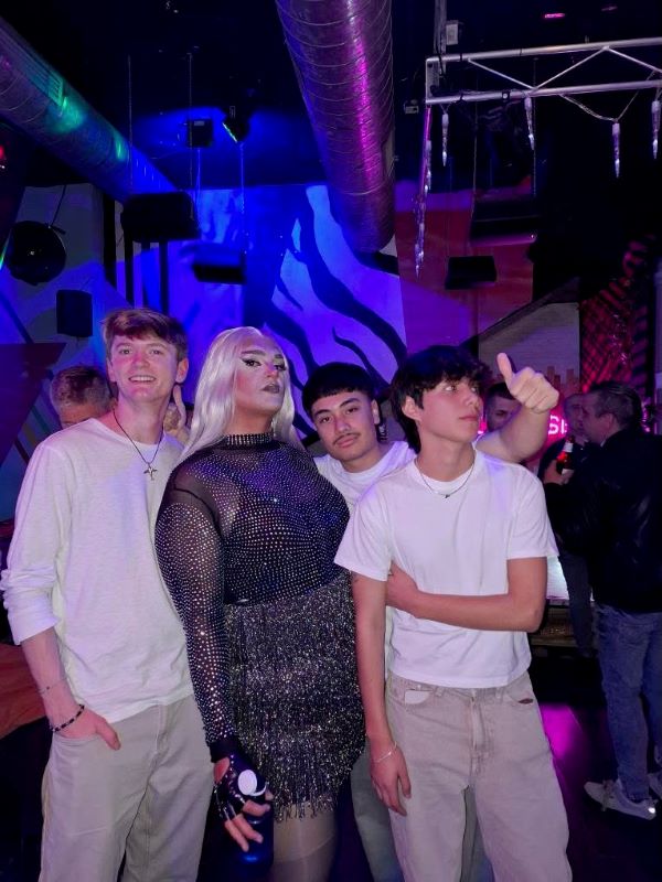 Four people standing together in a darkly-lit indoor space and smiling at the camera