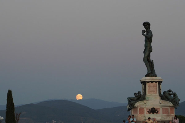 Full moon in the sky over a statue