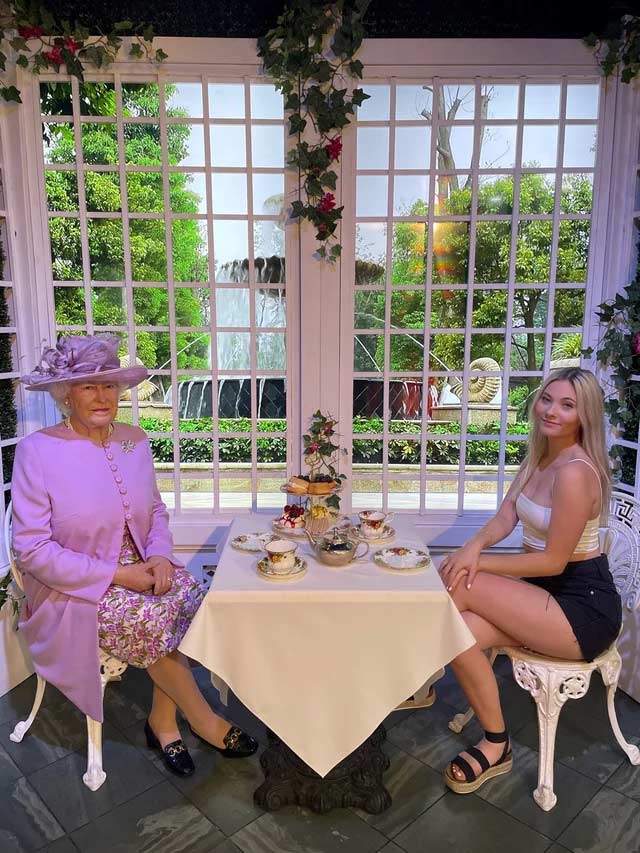 Photo with wax figure of the Queen having tea at Madame Tussads