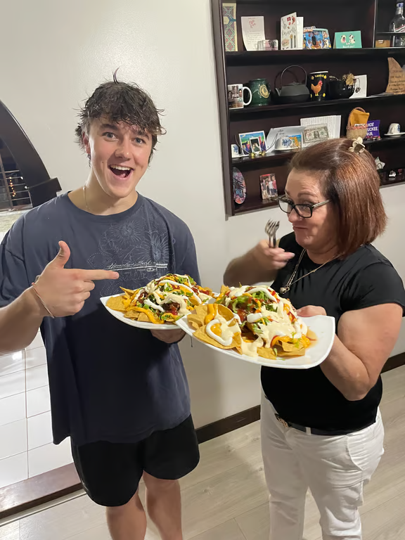 Study abroad student posing for photo with host mother and a their plate of nachos
