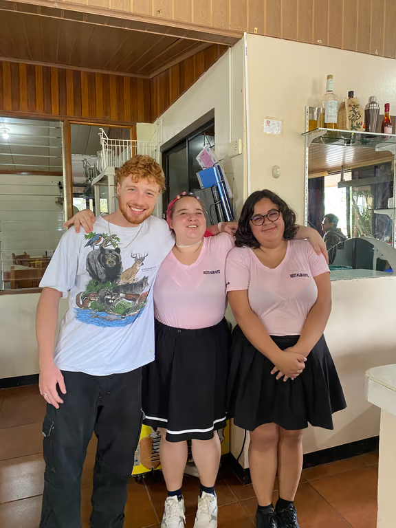 Study abroad student posing for photo with two servers